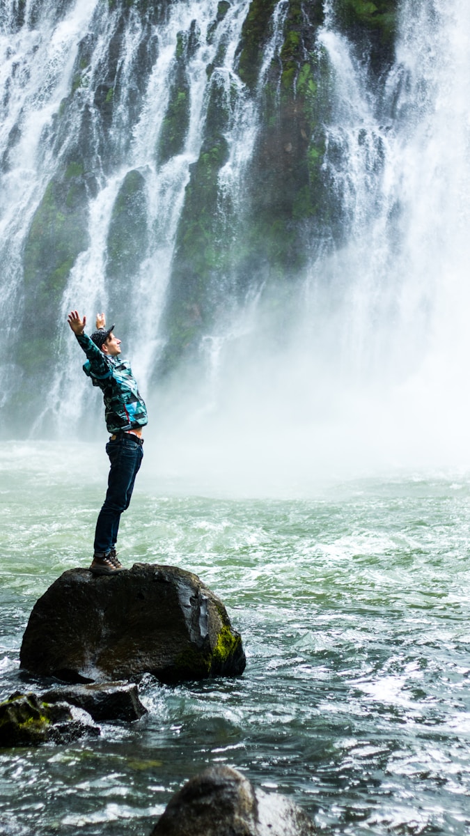 man standing on black rock surrounded body of water take your healing to the next level